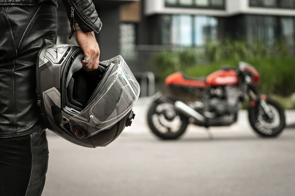 Photo Man with helmet in hand walking towards motorbike