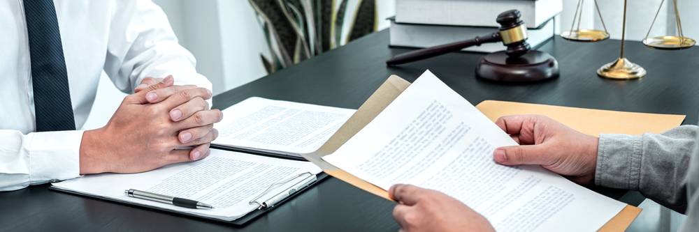 Photo of a man with papers in hand sitting at the desk