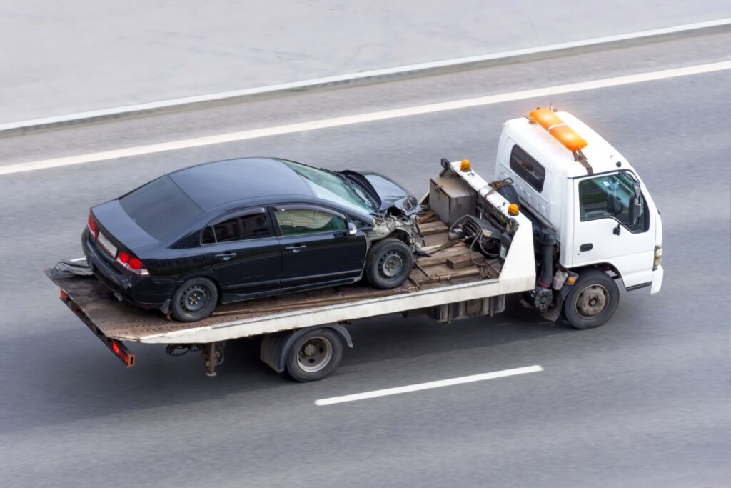 Car wrecked after an accident involving a trailer truck being transported on a highway