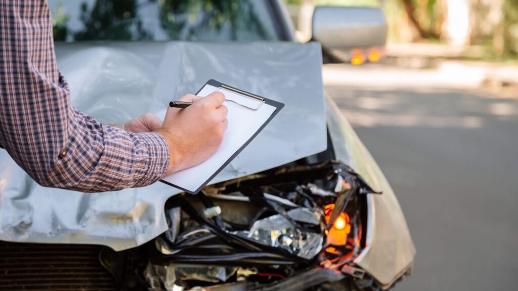 Insurance agent looking at destroyed car in road traffic accident crash