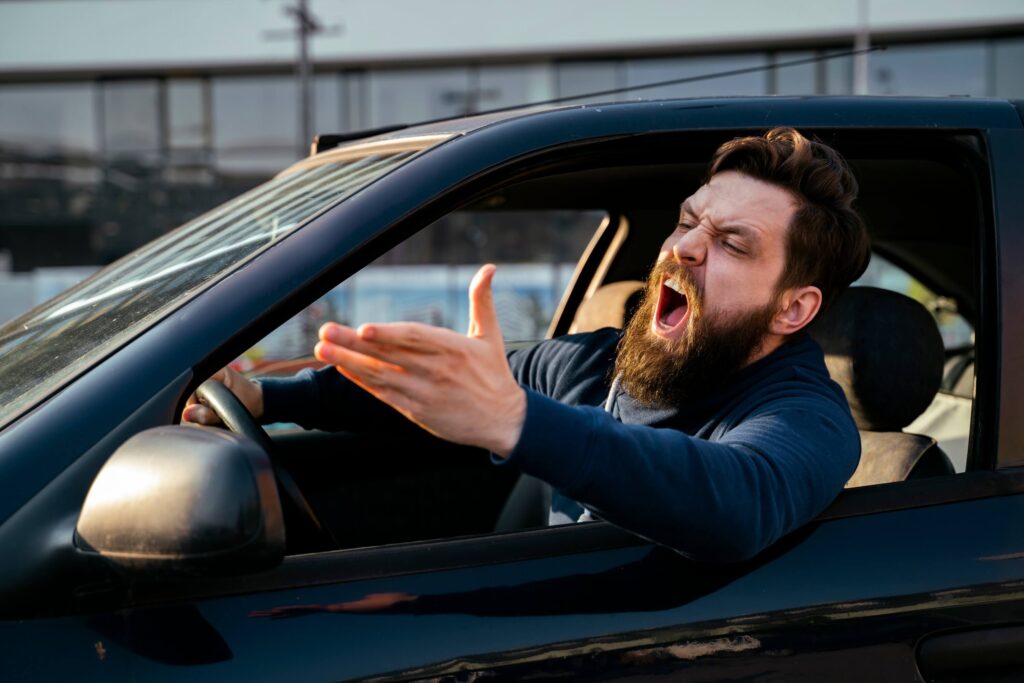 Road of angry young man with beard, screaming from the car near shot