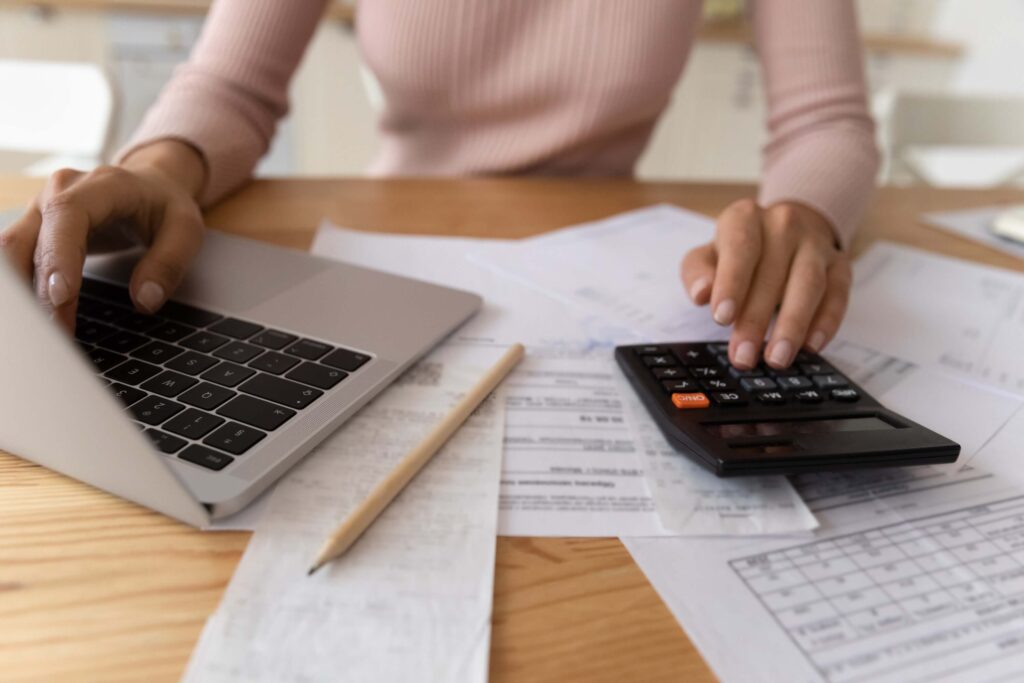 Young woman typing on computer keyboards and digital calculator